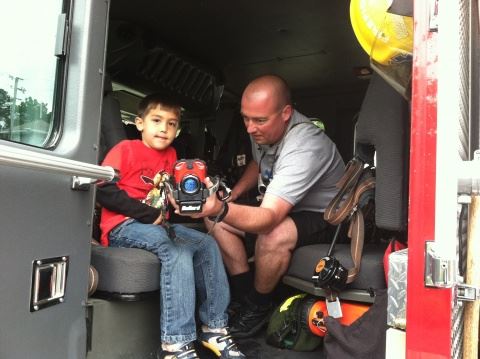 Firefighter Showing Boy Fire Truck Equipment