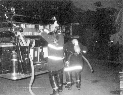 Firefighters in Full Gear Behind Fire Truck